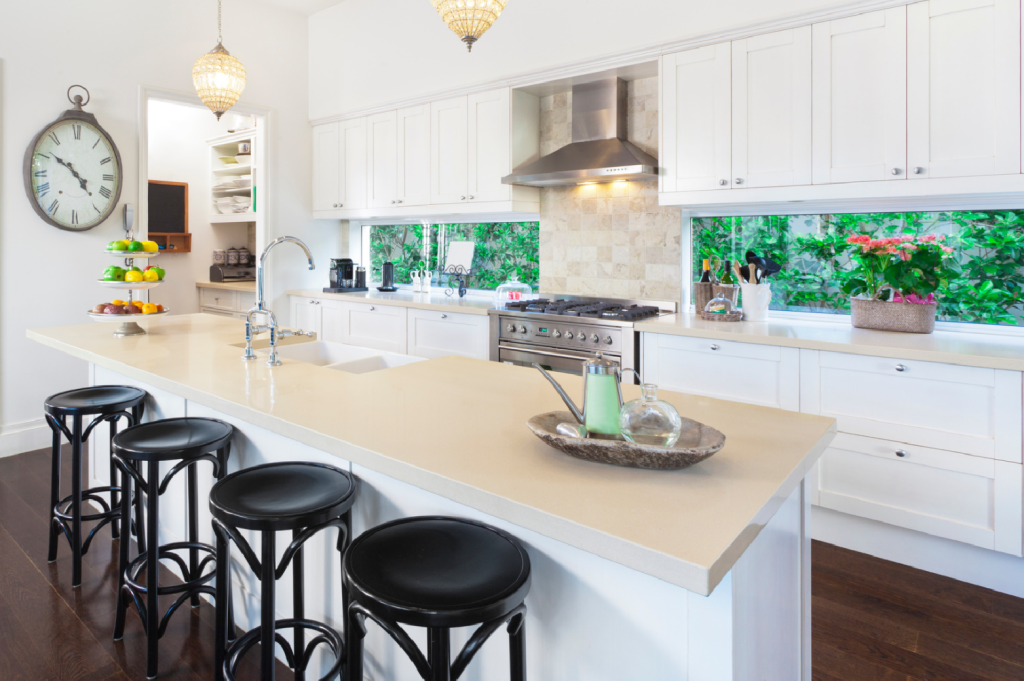 A neat kitchen with bar stools and a clock on the wall