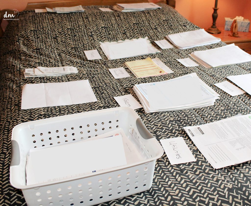 a bed covered with papers sorted into piles with index cards as labels