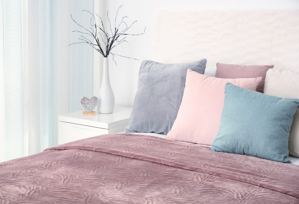 a bed with a purple comforter and colorful pillows.