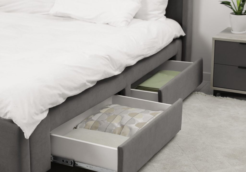 Storage drawers with bedding under modern bed in room. Space for text
