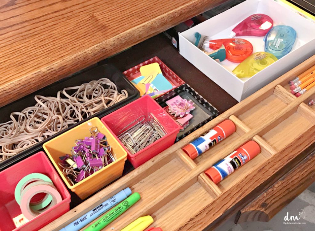 a drawer in a desk with office supplies in small containers