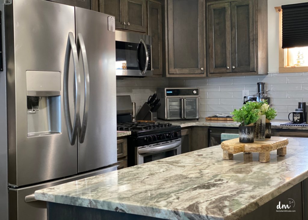 A modern kitchen with dark wood cabinets, stainless steel appliances, and a clean marble countertop
