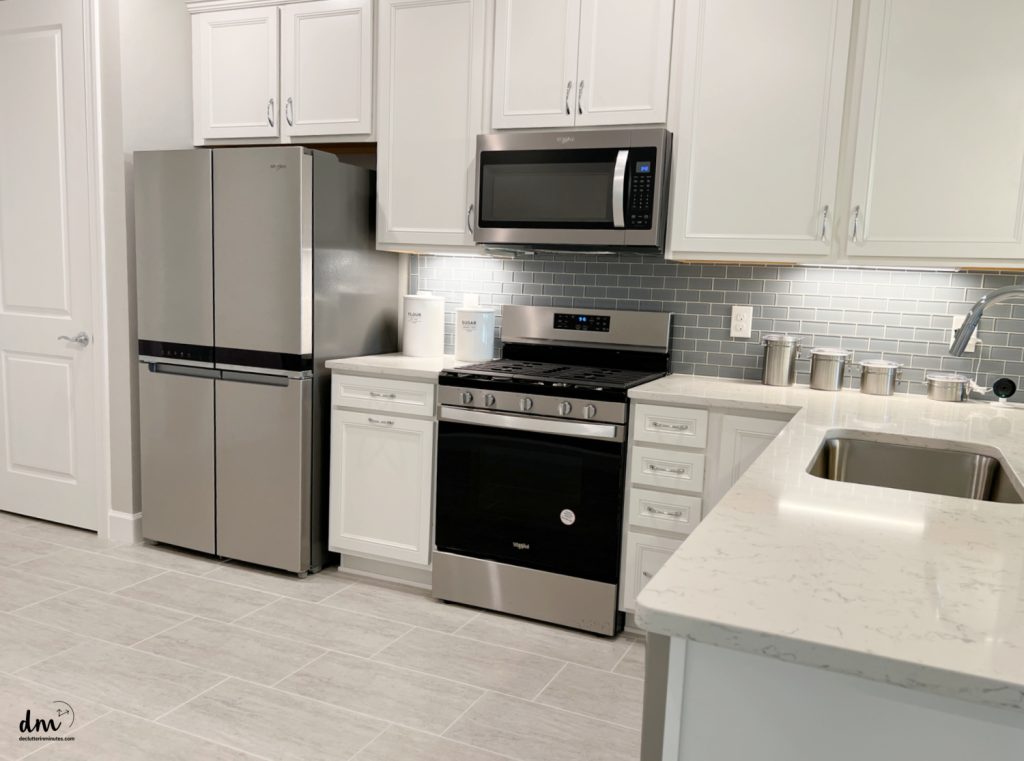 a neat and organized kitchen with steel appliances and white cabinets