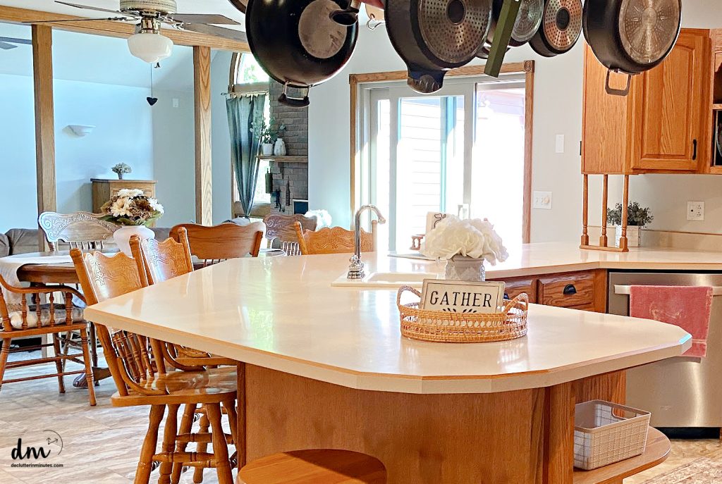 a neat kitchen with a basket on the counter and pots hanging from the ceiling