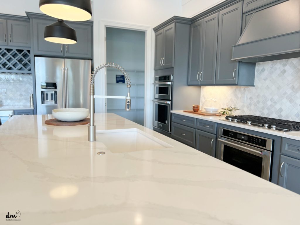 a neat kitchen with grey cabinets and a white marble counter