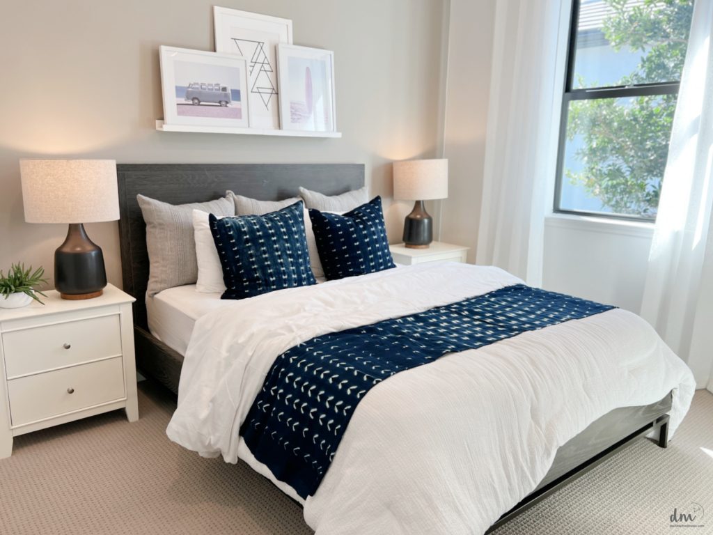 a white bed with blue pillows in a neat and organized bedroom