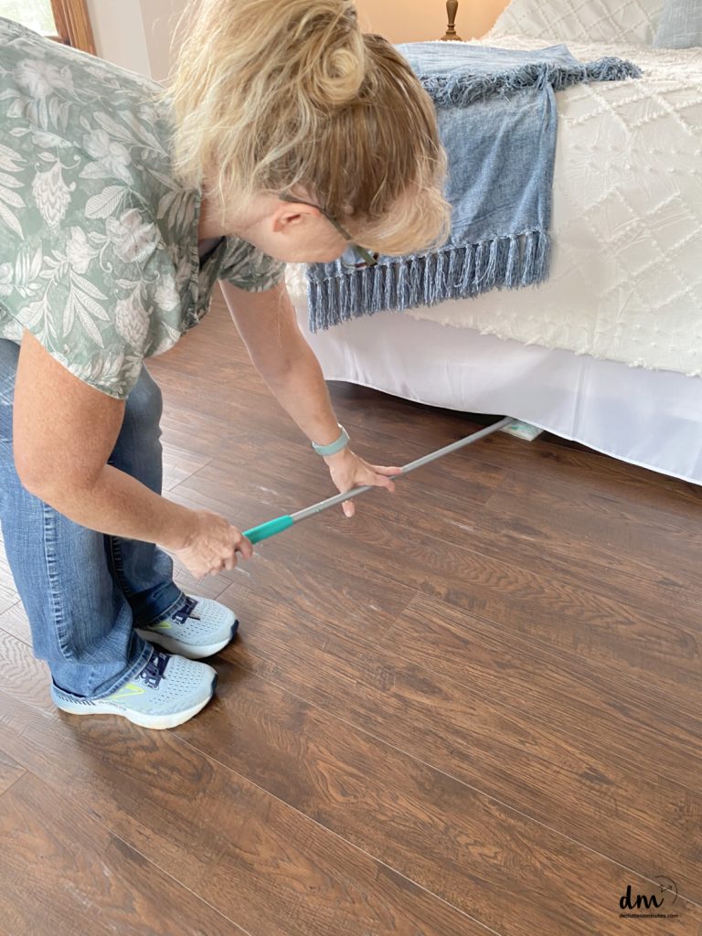 a woman cleaning under a bed in a bedroom 