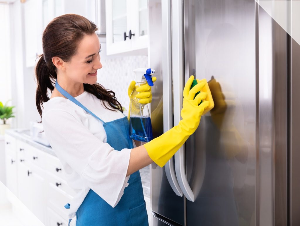 a woman in yellow gloves cleaning the outside of a fridge