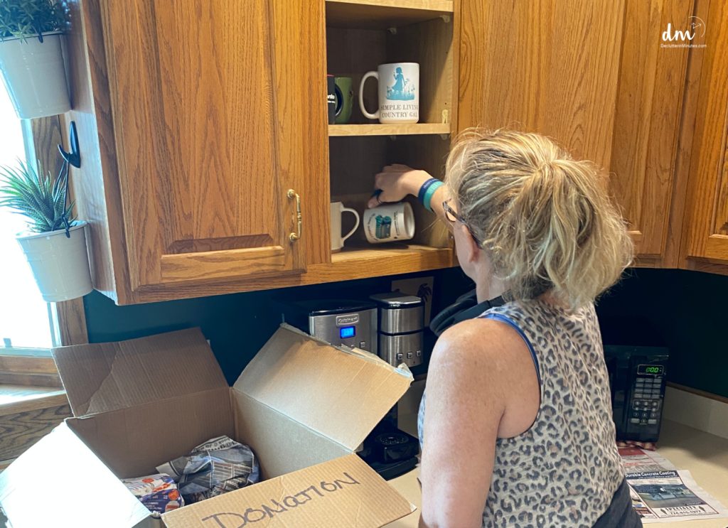 a woman packing up coffee cups with a donation box in a kitchen
