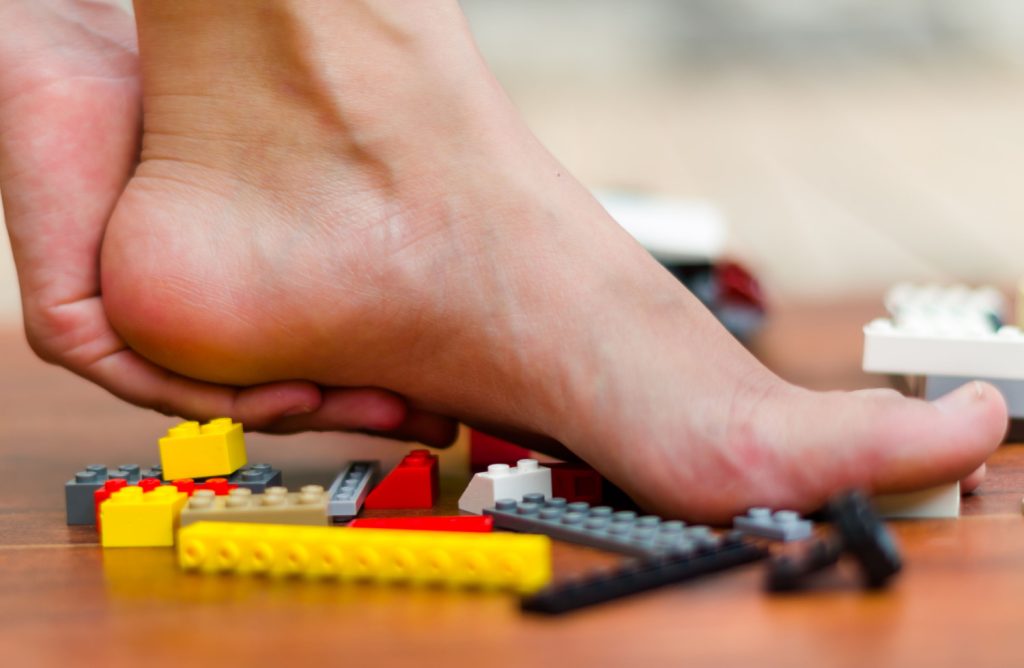 holding foot after stepping on legos on the floor