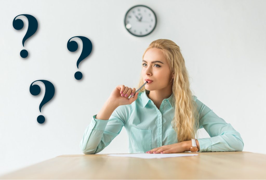 woman with a pen to her mouth thinking at a table