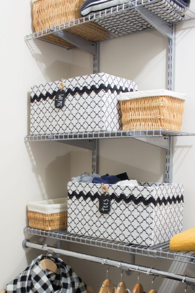 Image that shows boxes covered with cloth and labeled swim. Box is placed on a wire shelf in a bedroom closet.