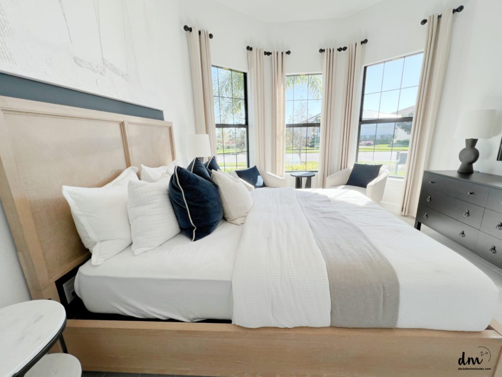 a bedroom that is neat and organized with sitting chairs near to a window