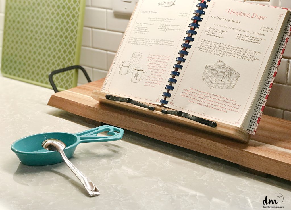 a cookbook on a stand with a spoon on a dish in front