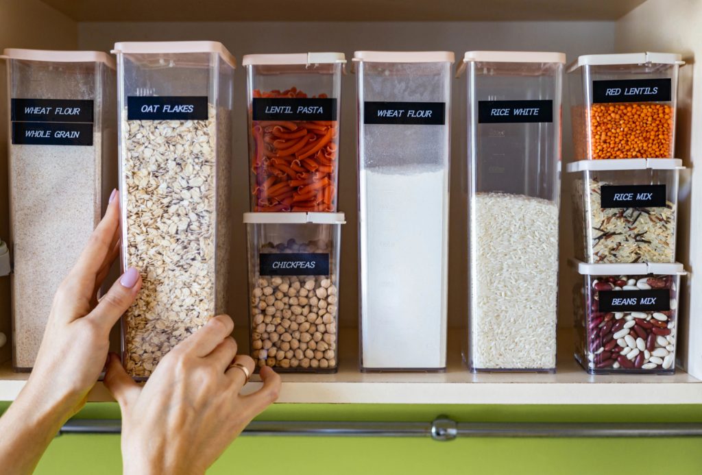 hands reaching for containers that are labeled and neat on a shelf