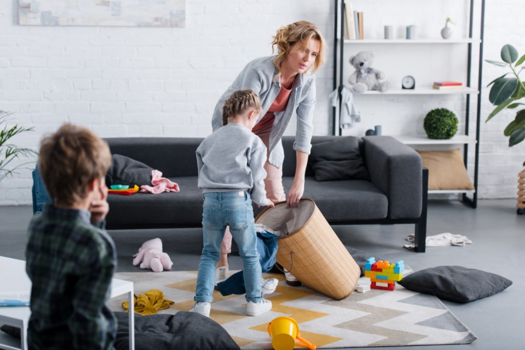 tired mom cleaning a family room with her kids