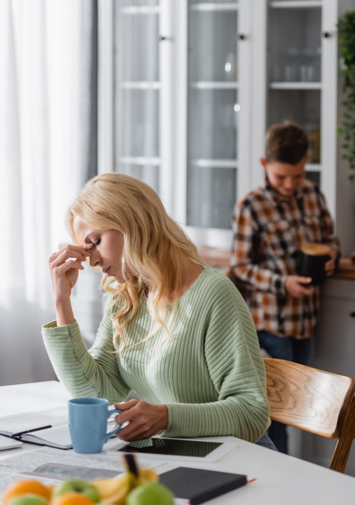 tired mom in the morning with son behind her