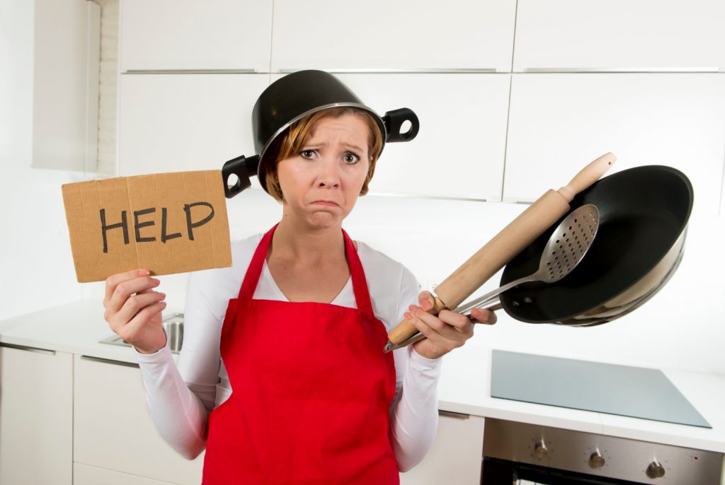 woman in red apron holding kitchen gadgets and a HELP sign