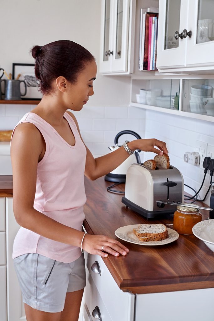 young woman making breakfast toast bread with toaster at home kitchen
