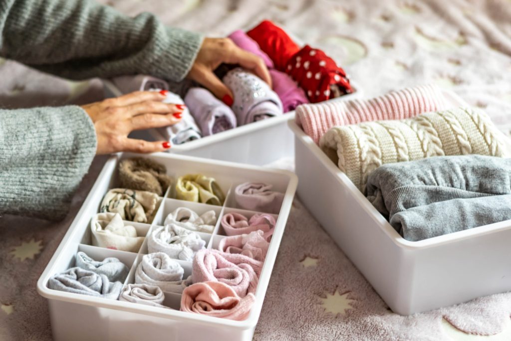 woman putting clothes away into organizing tubs