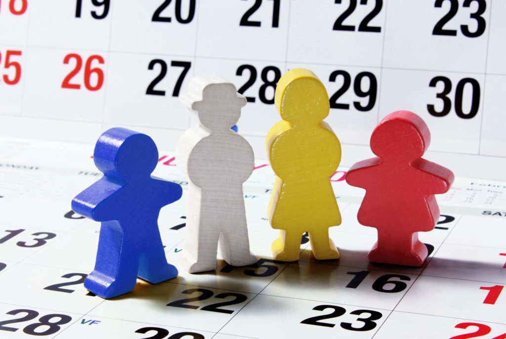 4 wood people standing on a paper calendar 