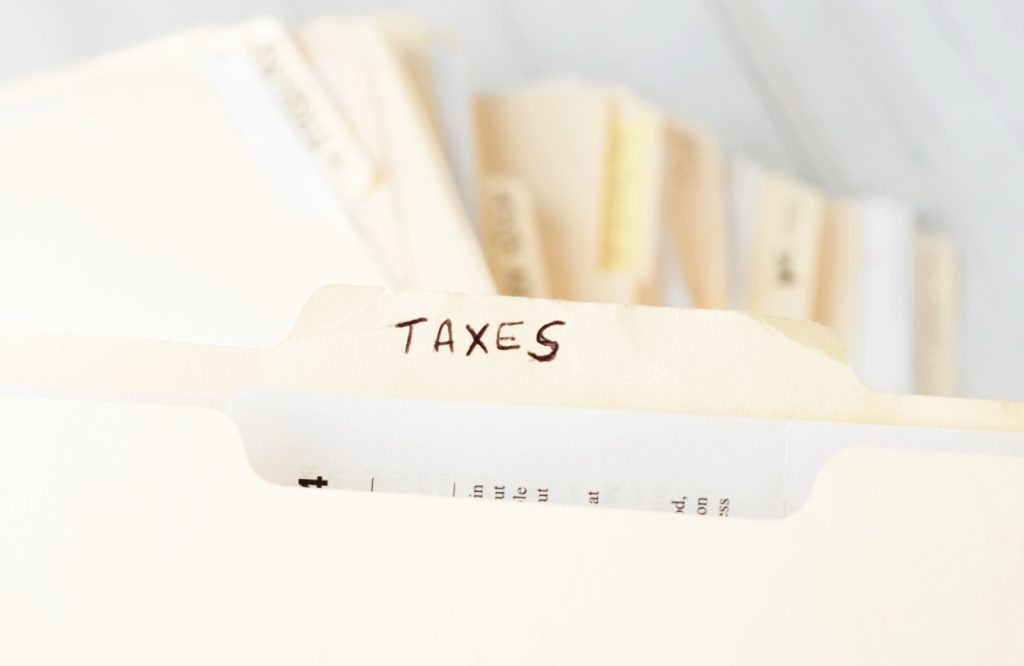 a file folder labeled taxes in a pile of random files