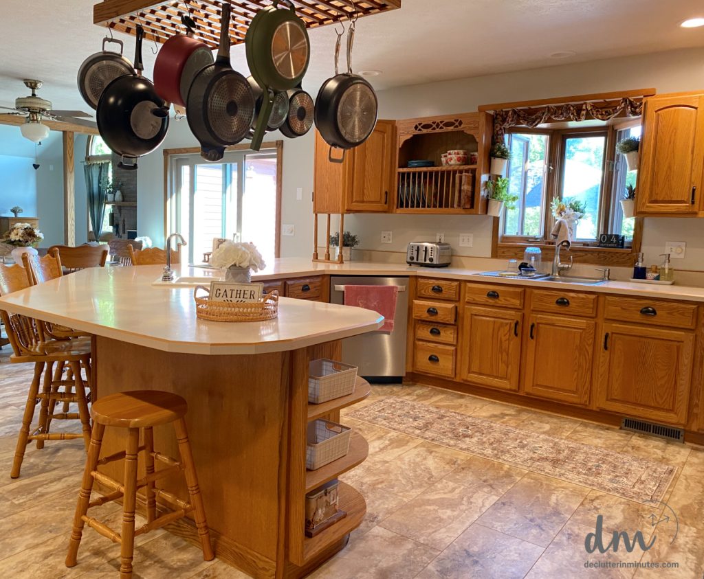A kitchen with wooden cabinets, a spacious island, and a hanging pot rack