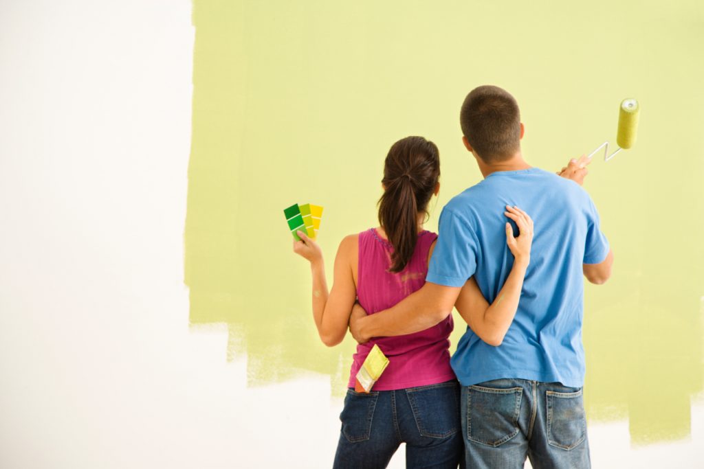 couple painting a bedroom light green
