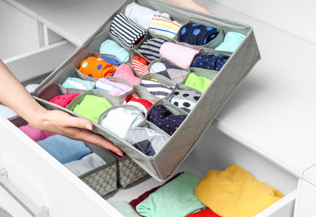 hands holding a drawer organizer filled with folded clothes