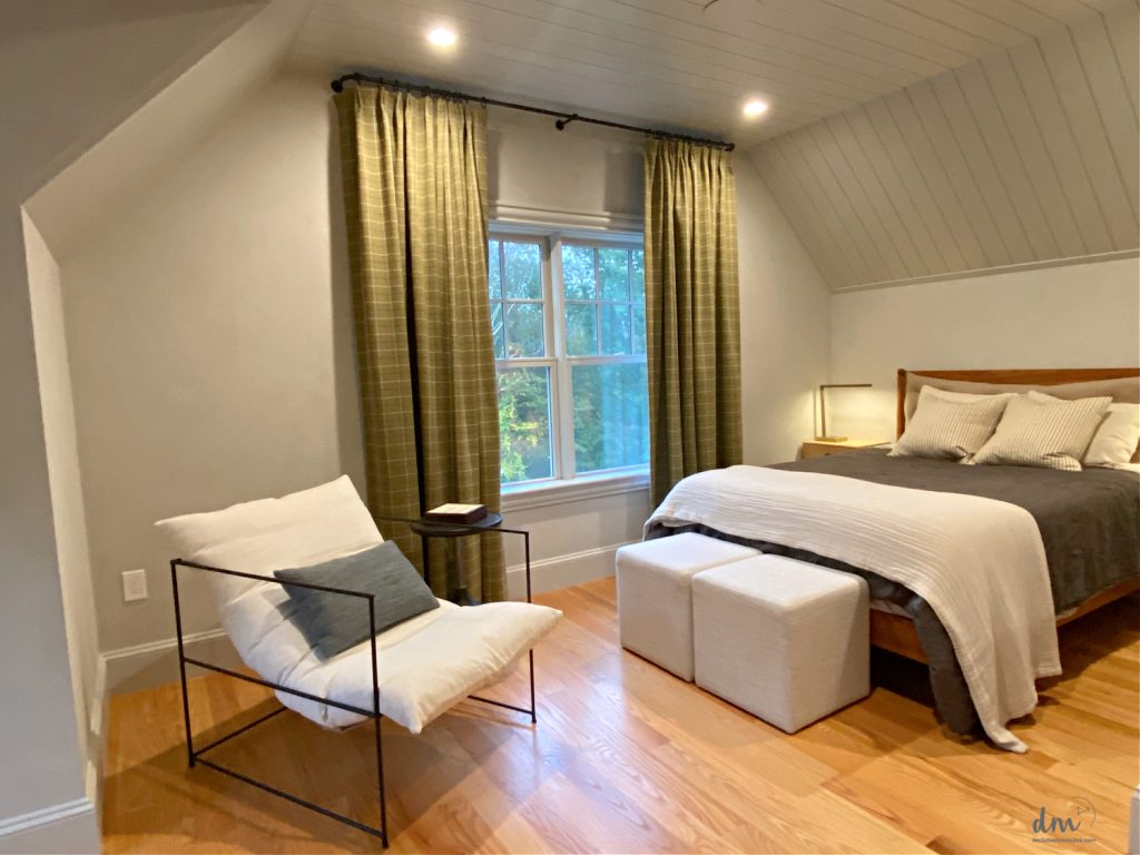 a bed near to a window with a reading chair in the corner