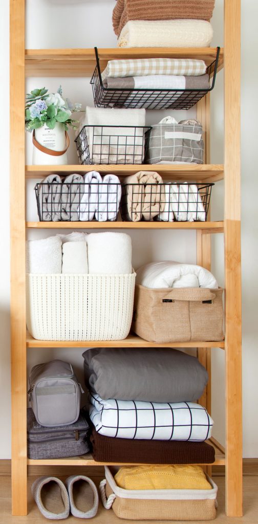 a linen closet organized with bins and baskets on shelves