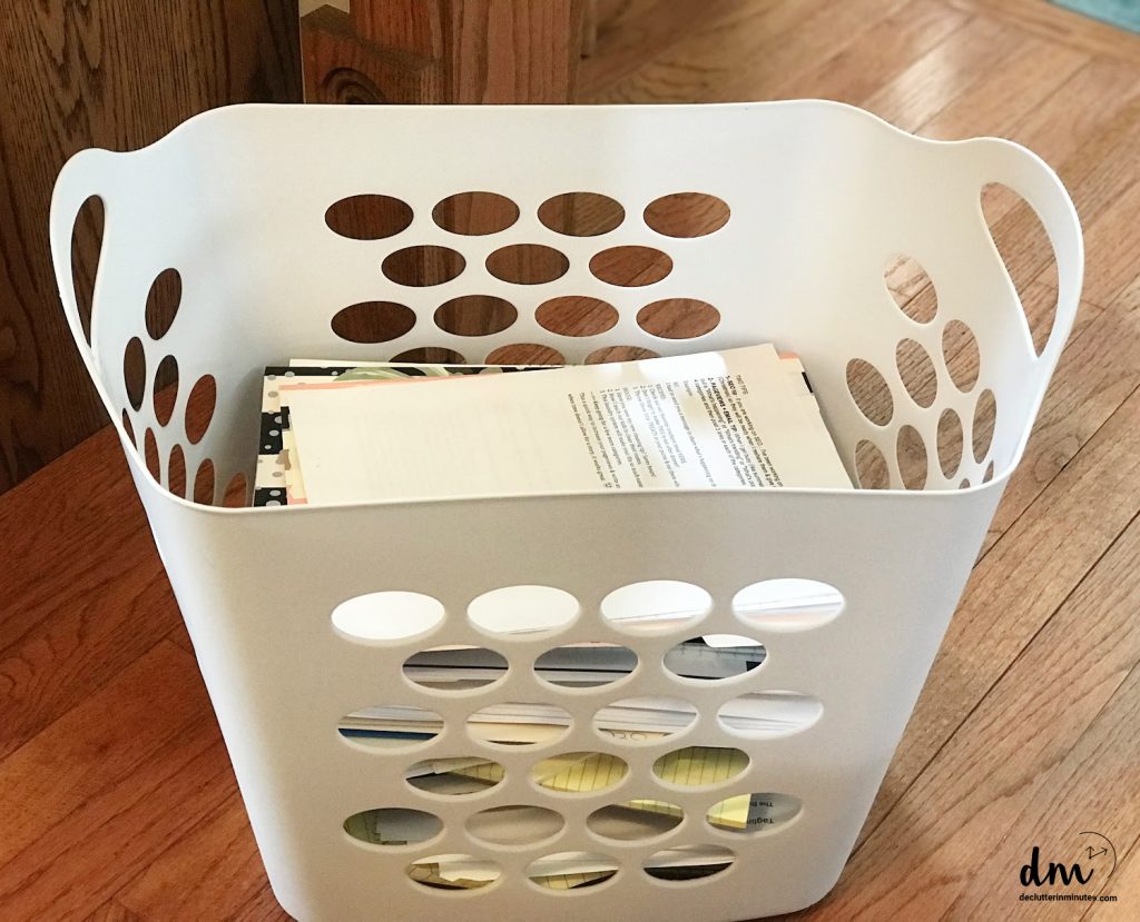 a white laundry basket filled with paper clutter waiting to be sorted and organized