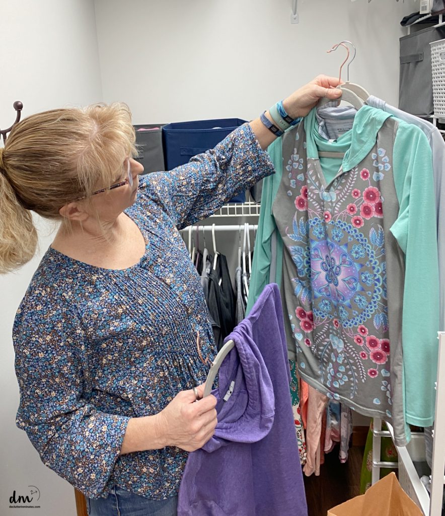 a woman holding up clothes on felt hangers in a closet