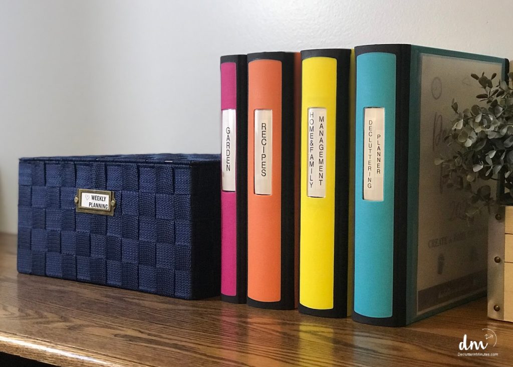 colored binders next to a blue woven box that are used to organized papers and recipes