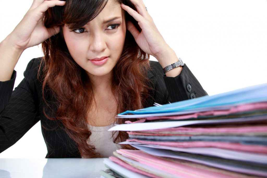 young business woman with many paper stressed at work. Isolated over white background