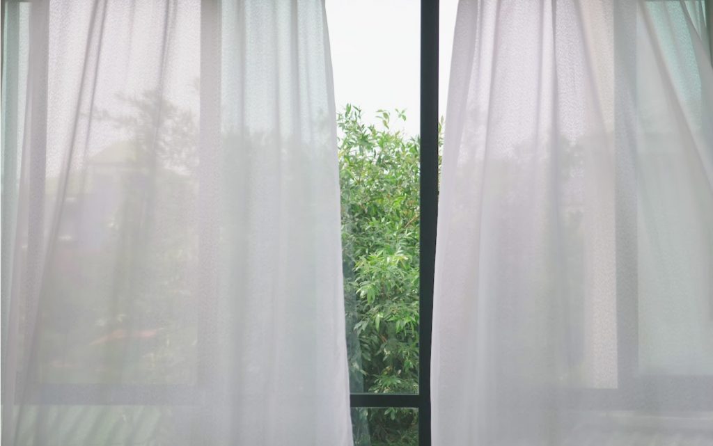 window that is opened with curtains blowing copy