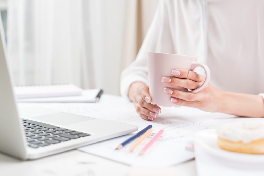 woman holding a cup of coffee at her home desk