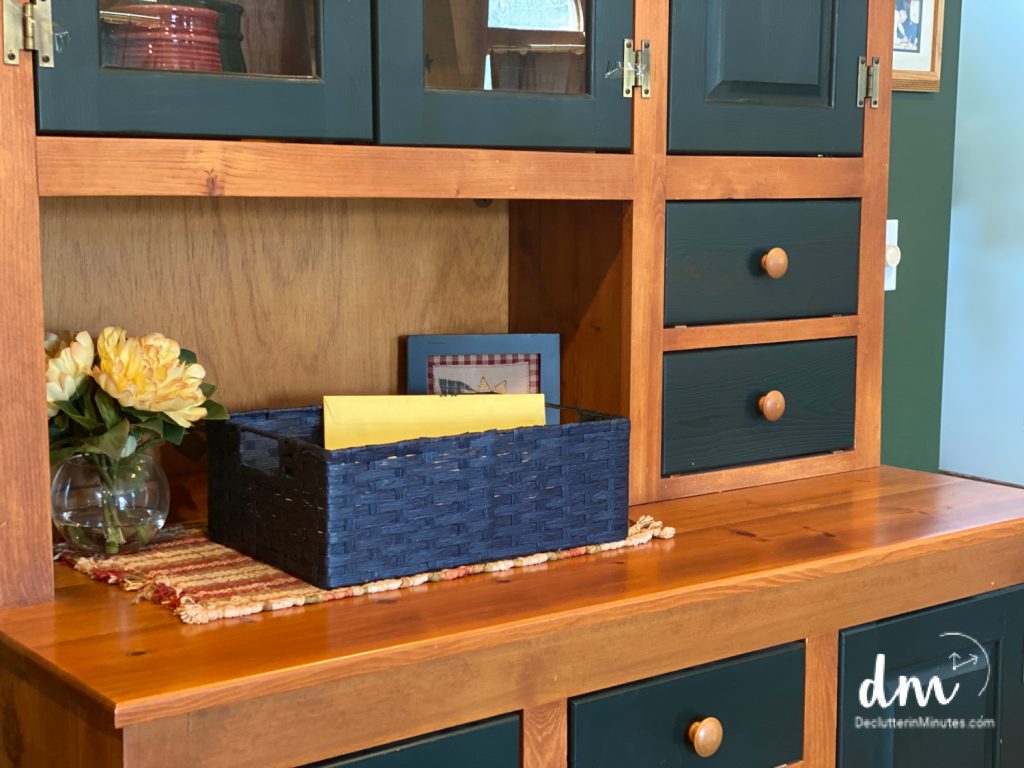 A wooden hutch with a navy blue woven basket holding mail and papers