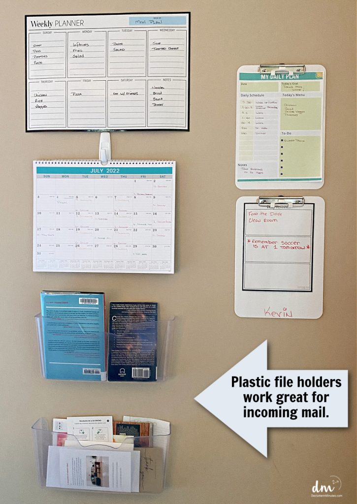 a wall layout of a family command center with plastic wall bins, clipboards and a calendar