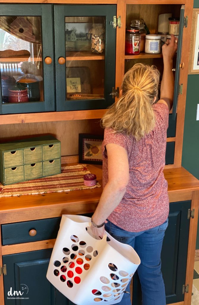 a woman putting items away holding a basket for home reset