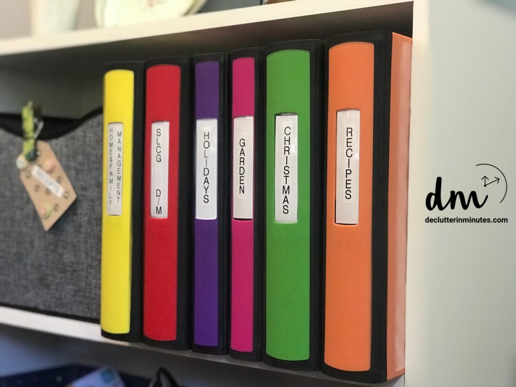 Color-coded binders labeled for various categories like recipes, Christmas, and holidays, neatly organized on a shelf