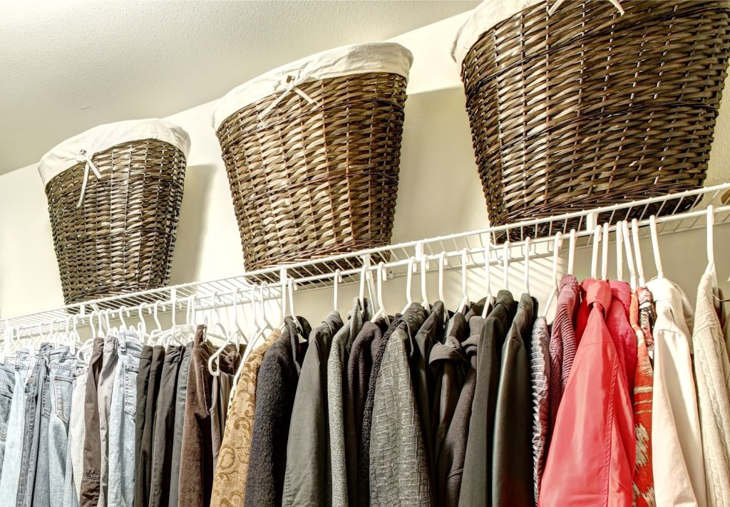 Walk-in closet with clothes on hangers and wicker baskets