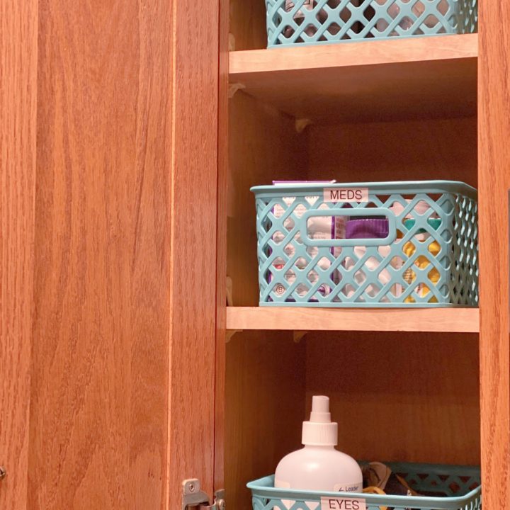 a cabinet with 3 blue baskets labeled eyes, meds, first aid copy