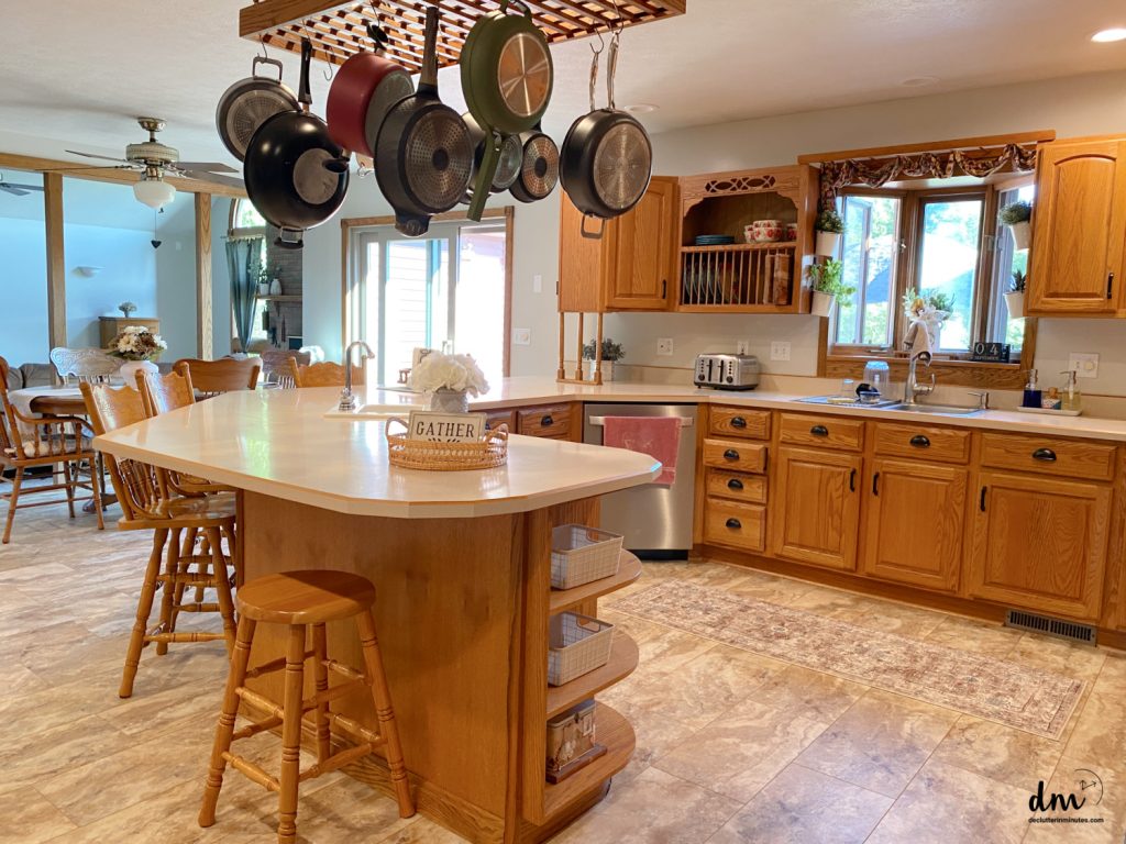 A kitchen featuring a hanging pot rack, wooden cabinets, and a central island with seating and storage