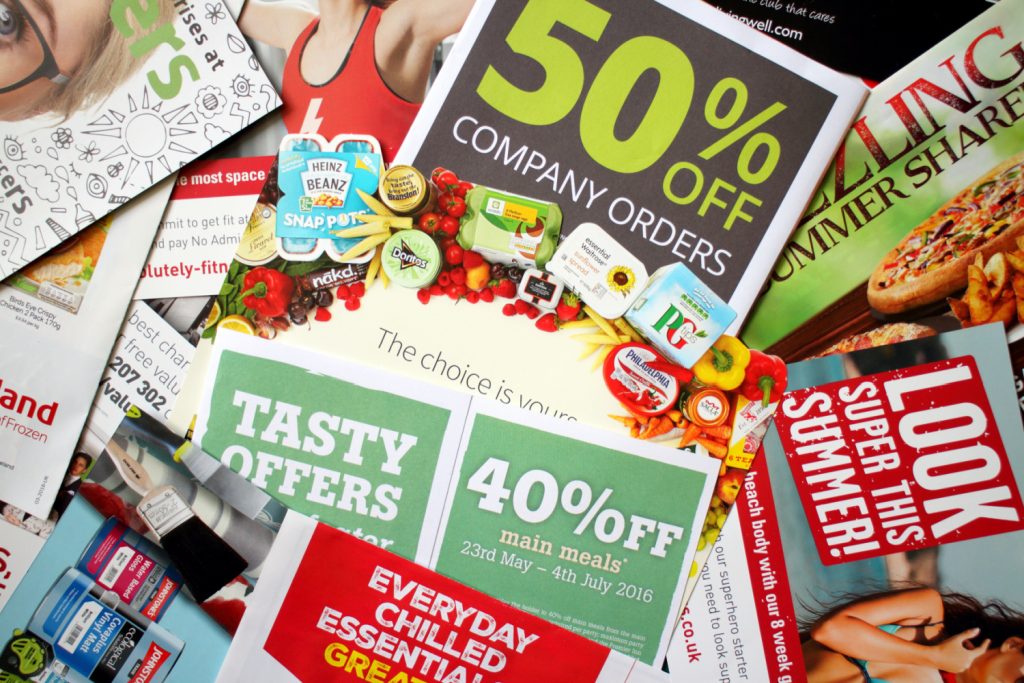 A pile of colorful junk mail and advertisements, including offers like "50% off company orders" and "40% off main meals
