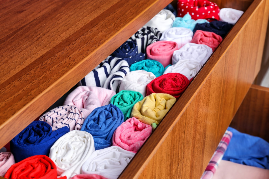 Image that shows clothes rolled up and sorted vertically in a drawer.
