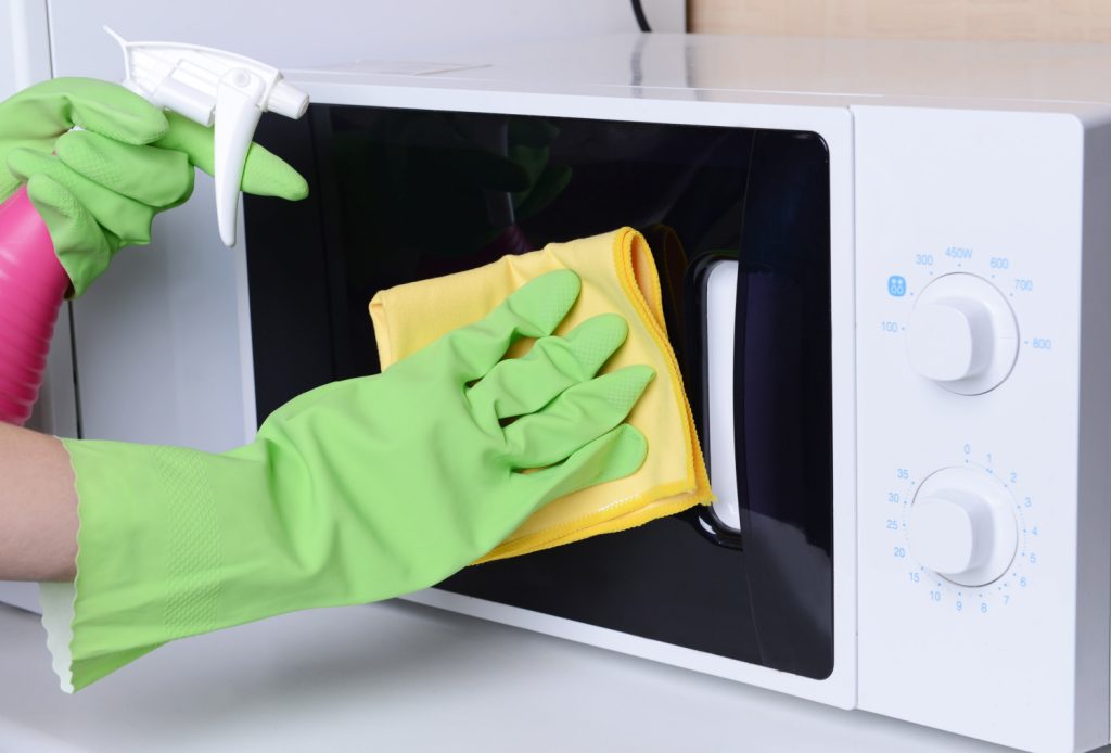 Cleaning microwave oven in kitchen close-up