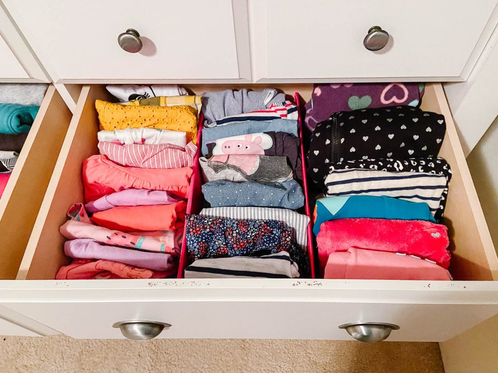Image that shows a clothes in a dresser sorted by a divider and clothes facing vertically.