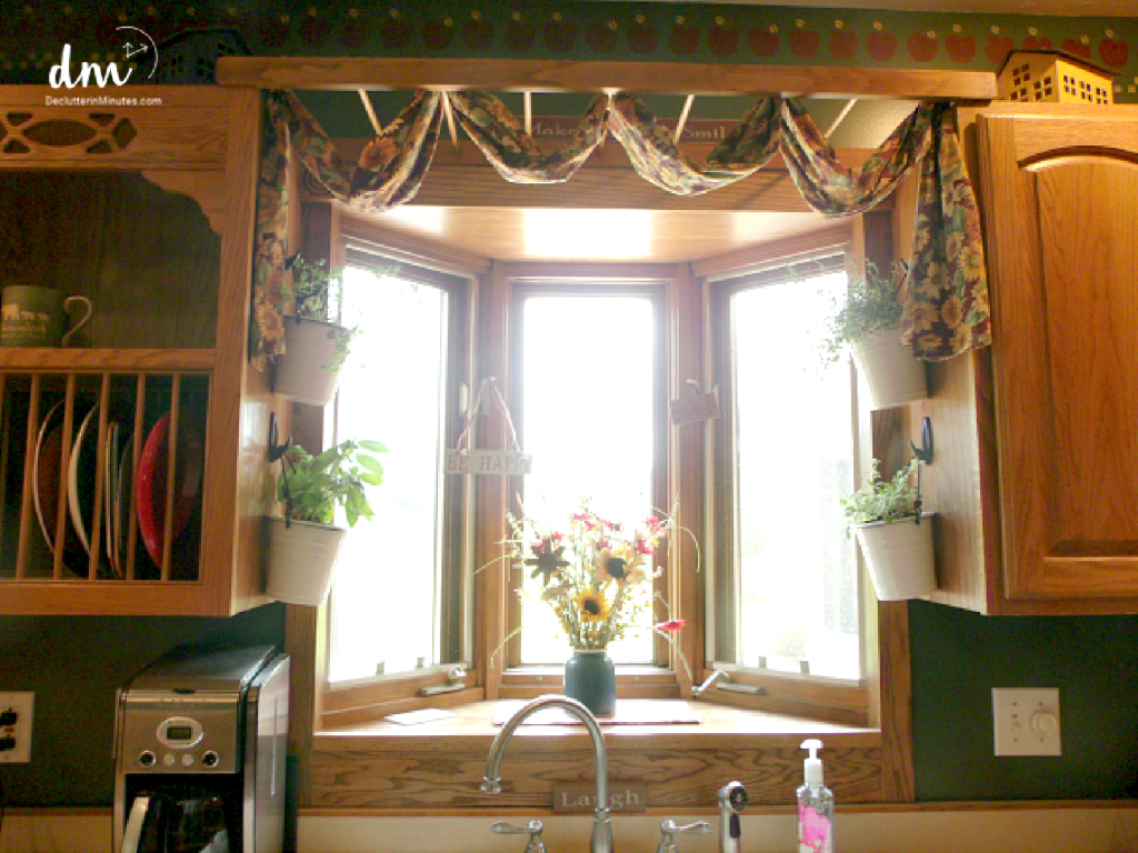 a kitchen window with hanging baskets of plants