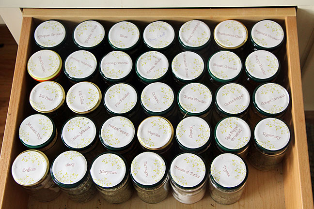 labeled glass spice jars in alphabetical order in a drawer